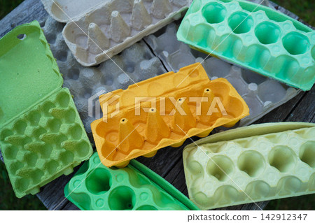 Collection of used colorful egg trays on vintage old wooden planks template Collection of used colorful egg trays on vintage old wooden planks template 142912347