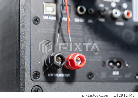 A close up view of audio speaker binding posts with bare copper wire ends prepared for connection to a home sound system amplifier to enable high fidelity music playback equipment A close up view of audio speaker binding posts with bare copper wire ends prepared for connection to a home sound system amplifier to enable high fidelity music playback equipment 142912443