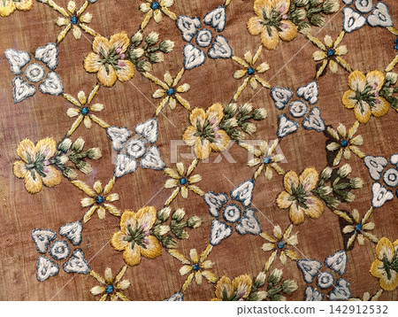 Detailed floral embroidery pattern on vintage brown silk fabric Detailed floral embroidery pattern on vintage brown silk fabric 142912532
