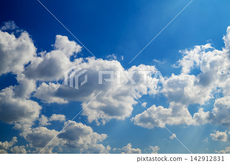 fluffy cloud masses filling the blue sky with soft sunlight rays shining through fluffy cloud masses filling the blue sky with soft sunlight rays shining through 142912831
