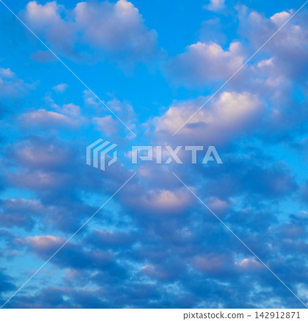 soft pink and white cumulus clouds across a blue sky during sunset time soft pink and white cumulus clouds across a blue sky during sunset time 142912871
