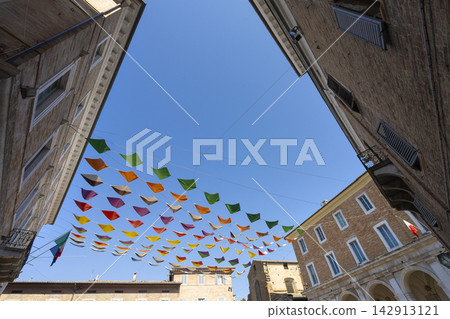 Colorful triangular flags are strung across a small square in Urbino, Italy 142913121