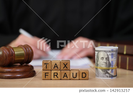 Tax fraud investigation with judges gavel and cash in close-up setting Tax fraud investigation with judges gavel and cash in close-up setting 142913257