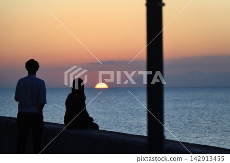 一對情侶在欣賞海上日落。 一對情侶在欣賞海上日落。 142913455