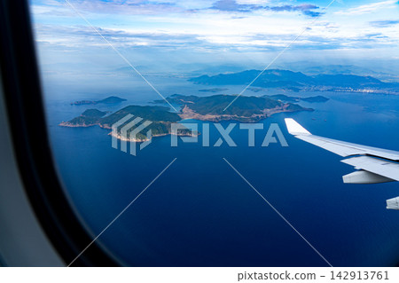 Scenic Aerial View of Serene Islands and Vast Ocean from Airplane Window, Capturing Nature's Beauty and the Tranquility of Remote Landscapes. Scenic Aerial View of Serene Islands and Vast Ocean from Airplane Window, Capturing Nature's Beauty and the Tranquility of Remote Landscapes. 142913761