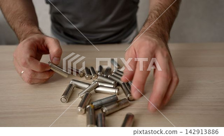 Male hands checking pile of old alkaline batteries for recycling Male hands checking pile of old alkaline batteries for recycling 142913886