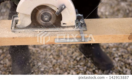 Circular saw blade cutting wooden plank with sawdust in motion Circular saw blade cutting wooden plank with sawdust in motion 142913887