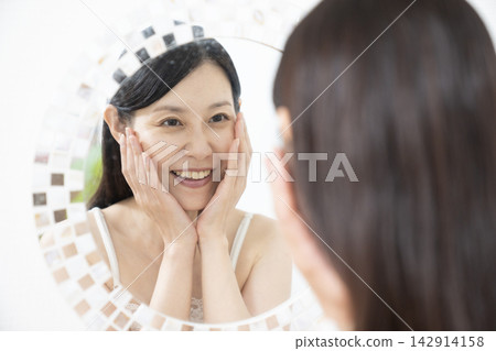 一位嫁接了睫毛的女士正在照鏡子。 一位嫁接了睫毛的女士正在照鏡子。 142914158
