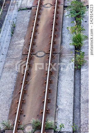 A high-angle, aerial view of the linear railway infrastructure, showing the concrete track bed and rails of a slab track. A high-angle, aerial view of the linear railway infrastructure, showing the concrete track bed and rails of a slab track. 142914223
