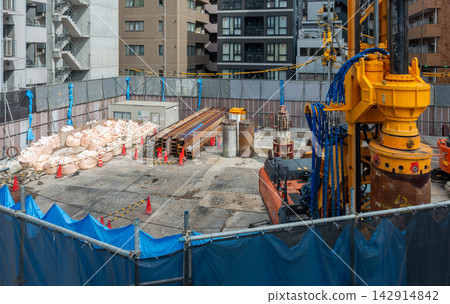 A panoramic view of an urban construction site: A full view of foundation work with pile drivers and materials lined up. A panoramic view of an urban construction site: A full view of foundation work with pile drivers and materials lined up. 142914842