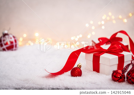 White Gift Box with Red Ribbon on Snowy Surface White Gift Box with Red Ribbon on Snowy Surface 142915046