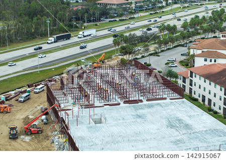 Industrial construction site with workers assembling metal frame building. Development of residential housing in America. Real estate market in the USA Industrial construction site with workers assembling metal frame building. Development of residential housing in America. Real estate market in the USA 142915067