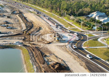 Driving traffic cars at roundabout intersection under construction. Building traffic circle on American road with moving cars Driving traffic cars at roundabout intersection under construction. Building traffic circle on American road with moving cars 142915068
