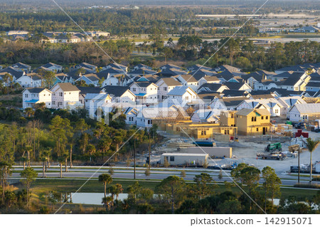 Aerial view of unfinished wooden frames of affordable houses under construction. Development of residential housing in American suburbs. Real estate market in the USA Aerial view of unfinished wooden frames of affordable houses under construction. Development of residential housing in American suburbs. Real estate market in the USA 142915071