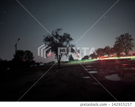 Starry night sky over rural landscape with light trails Starry night sky over rural landscape with light trails 142915257