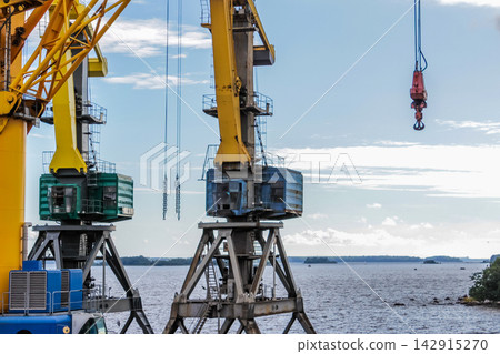 Stationary industrial cranes on a coal mining embankment. Containers and metal structures, industrial setting against the backdrop Stationary industrial cranes on a coal mining embankment. Containers and metal structures, industrial setting against the backdrop 142915270