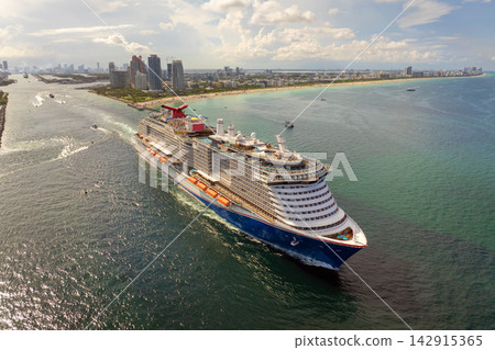 Large passenger cruise ship departing Miami port at sunset. Scenic view of South Beach waterfront with high-rise hotels and residential towers. Large passenger cruise ship departing Miami port at sunset. Scenic view of South Beach waterfront with high-rise hotels and residential towers. 142915365