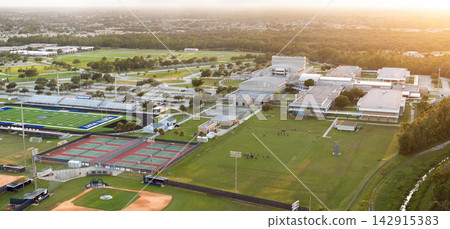 Sports education in USA schools. School children playing American football game during physical exercise on school stadium at sunset Sports education in USA schools. School children playing American football game during physical exercise on school stadium at sunset 142915383