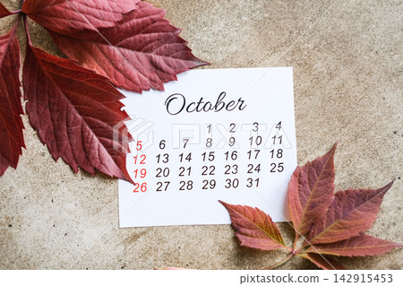 October calendar card with red autumn leaves on textured surface. Late fall planning, thanksgiving season 142915453