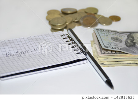 notepad with notes, pen, dollars and coins on a white background notepad with notes, pen, dollars and coins on a white background 142915625