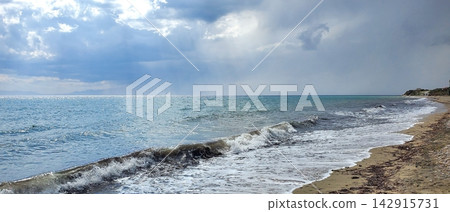 coastline of the sea after the storm. small waves and sun with clouds coastline of the sea after the storm. small waves and sun with clouds 142915731