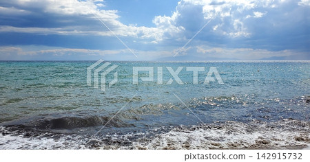 coastline of the sea after the storm. small waves and sun with clouds coastline of the sea after the storm. small waves and sun with clouds 142915732
