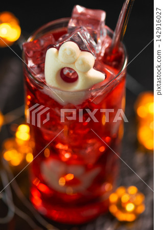Spooky Halloween red cocktail with marshmallow ghost and ice cubes festive drink Spooky Halloween red cocktail with marshmallow ghost and ice cubes festive drink 142916027