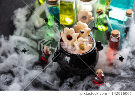 Halloween cauldron with spooky cookies and potion bottles surrounded by cobwebs and spiders Halloween cauldron with spooky cookies and potion bottles surrounded by cobwebs and spiders 142916065