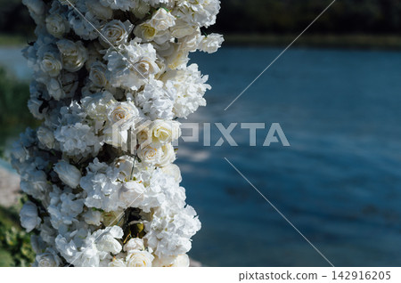 White rose floral arch detail for outdoor wedding ceremony by the lake. White rose floral arch detail for outdoor wedding ceremony by the lake. 142916205