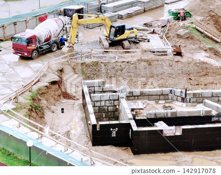 Construction Site With Excavator And Cement Truck Building Foundation In Muddy Urban Work Zone. Construction Site With Excavator And Cement Truck Building Foundation In Muddy Urban Work Zone. 142917078