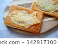 一種小吃，由金黃色的魚形鯛魚燒派組成，擺放在木盤上。 142917100