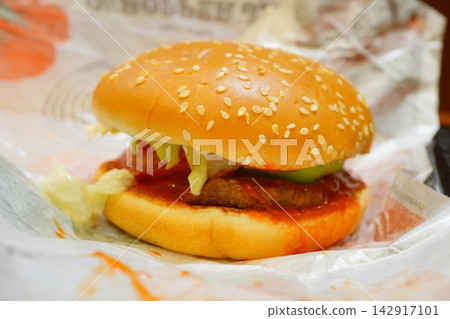 A hearty hamburger with a beef patty and vegetables sandwiched between sesame seed buns. A hearty hamburger with a beef patty and vegetables sandwiched between sesame seed buns. 142917101