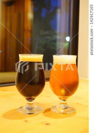 兩種精釀啤酒,一種是深色啤酒,一種是琥珀色啤酒,並排放在木桌上供人品嚐。 兩種精釀啤酒,一種是深色啤酒,一種是琥珀色啤酒,並排放在木桌上供人品嚐。 142917103