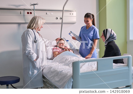 Caring medical staff support young patient in a modern hospital room during an uplifting check-up visit Caring medical staff support young patient in a modern hospital room during an uplifting check-up visit 142918069