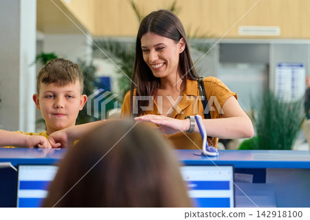 Woman and child engaging with staff at a service desk in a modern office environment Woman and child engaging with staff at a service desk in a modern office environment 142918100