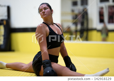 Female Boxer Athlete Stretching on Mat in Gym After Intense Boxing Training Session Female Boxer Athlete Stretching on Mat in Gym After Intense Boxing Training Session 142918129