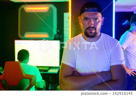 Serious Gamer Coach Standing With Arms Crossed in Neon Esports Gaming Room Serious Gamer Coach Standing With Arms Crossed in Neon Esports Gaming Room 142918145
