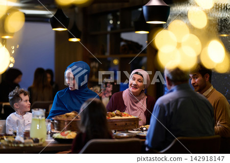Multigenerational Family Dinner With Women Wearing Hijab Sharing a Festive Meal and Conversation Multigenerational Family Dinner With Women Wearing Hijab Sharing a Festive Meal and Conversation 142918147