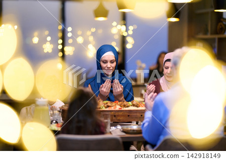 Muslim Family Saying Prayer Together During Iftar Dinner At Home With Festive Lights Muslim Family Saying Prayer Together During Iftar Dinner At Home With Festive Lights 142918149