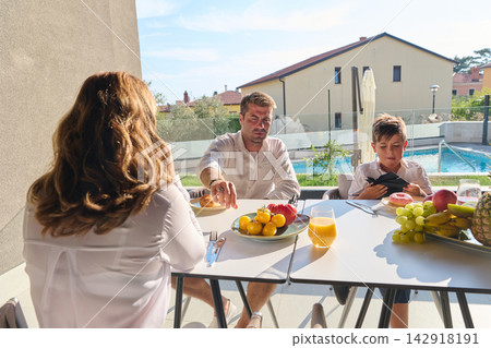 Family Breakfast On Poolside Terrace During Sunny Summer Morning With Father, Mother And Son Family Breakfast On Poolside Terrace During Sunny Summer Morning With Father, Mother And Son 142918191