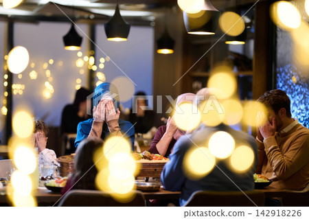 Multigenerational Muslim Family Saying Prayer Together at Iftar Dinner With Warm Lights Multigenerational Muslim Family Saying Prayer Together at Iftar Dinner With Warm Lights 142918226