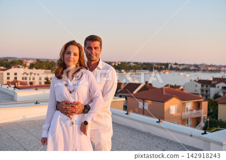 Middle-Aged Couple Embracing on Rooftop Terrace With Seaside View at Sunset Overlooking Marina and Town Middle-Aged Couple Embracing on Rooftop Terrace With Seaside View at Sunset Overlooking Marina and Town 142918243