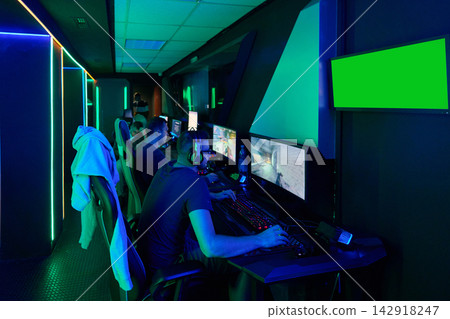 Team of Gamers Playing PC Games in Neon Esports Gaming Lounge With Headsets and Monitors Team of Gamers Playing PC Games in Neon Esports Gaming Lounge With Headsets and Monitors 142918247