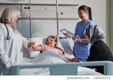 Healthcare team provides support to young patient in hospital room during afternoon visit Healthcare team provides support to young patient in hospital room during afternoon visit 142918255