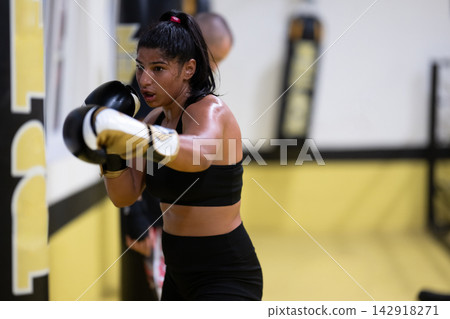 Female Boxer Training in Gym Throwing Punches During Intense Fitness Boxing Workout Session Female Boxer Training in Gym Throwing Punches During Intense Fitness Boxing Workout Session 142918271