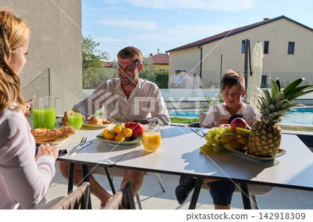 Family Breakfast on a Poolside Terrace With Father and Son Enjoying Fresh Fruit and Juice Family Breakfast on a Poolside Terrace With Father and Son Enjoying Fresh Fruit and Juice 142918309