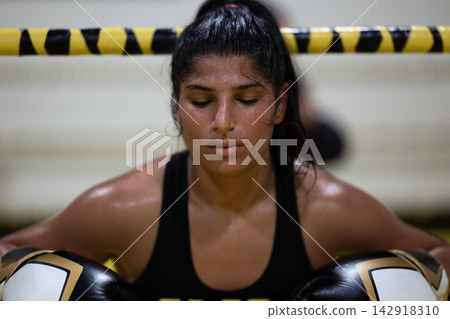 Tired Female Boxer Resting In Ring After Intense Training Session With Gloves On Tired Female Boxer Resting In Ring After Intense Training Session With Gloves On 142918310