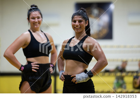 Two Female Athletes Smiling After Boxing Training Session in a Gym Ring Two Female Athletes Smiling After Boxing Training Session in a Gym Ring 142918353