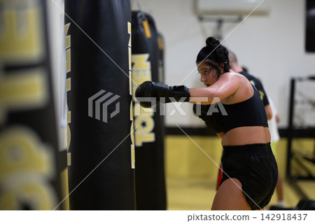 Female Boxer Training With Punching Bag During Intense Fitness Gym Workout Session Female Boxer Training With Punching Bag During Intense Fitness Gym Workout Session 142918437