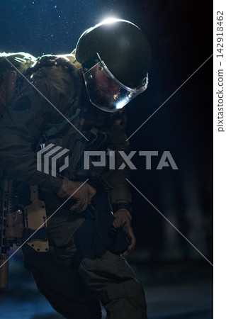 Tactical Soldier In Riot Gear With Helmet And Visor Preparing Equipment During Night Operation Tactical Soldier In Riot Gear With Helmet And Visor Preparing Equipment During Night Operation 142918462